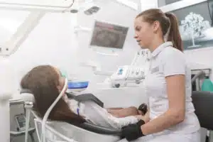Patient speaking with a dental professional beside the treatment chair