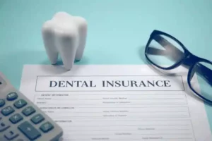 Dental insurance paperwork with a tooth model and glasses