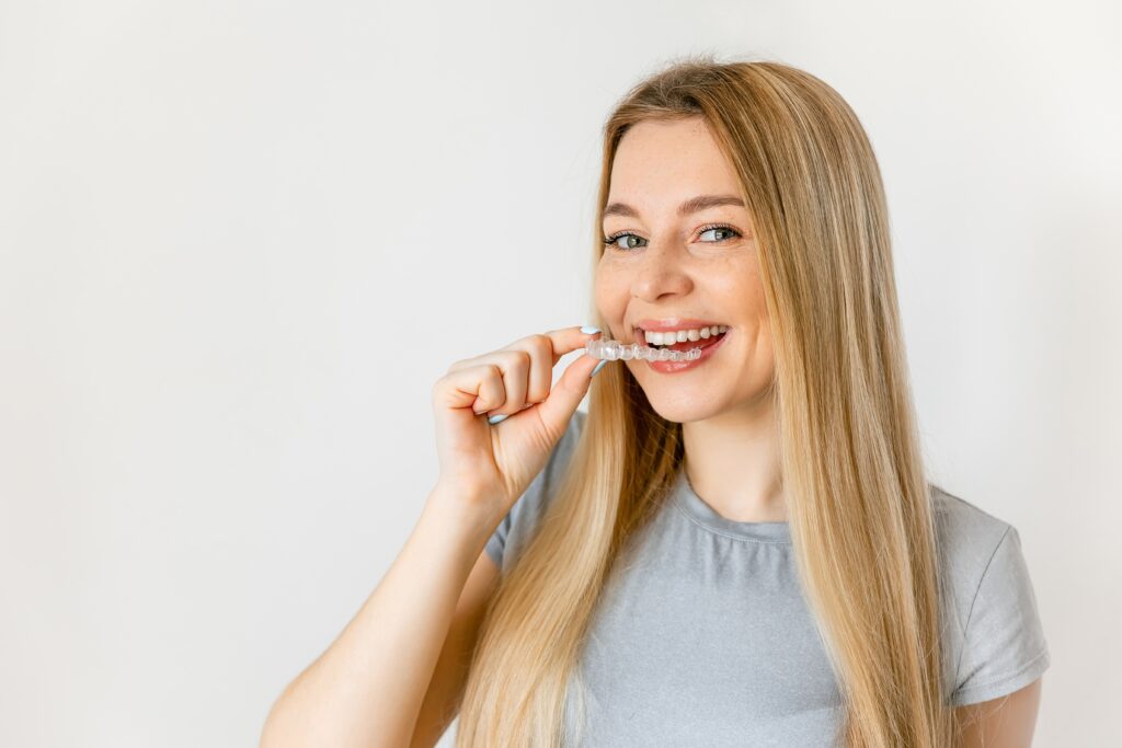 Woman placing a clear dental aligner over her teeth
