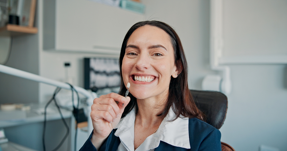 Woman holding a clear dental aligner beside her smile